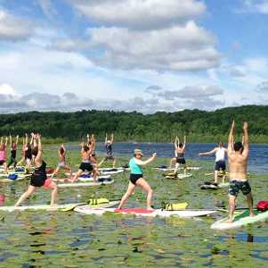 a group of people doing yoga on kayaks on a lake