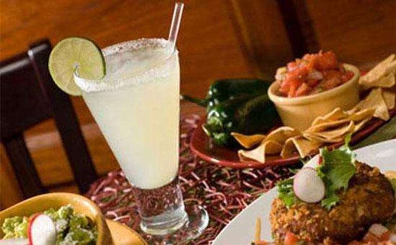 large margarita surrounded by chips, salsa, and guacamole