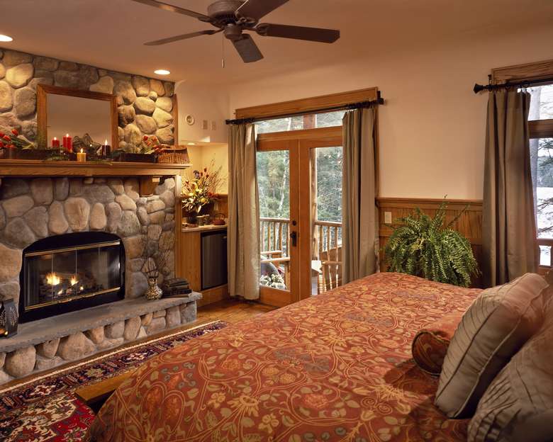 a bedroom with a  stone fireplace and sliding glass doors