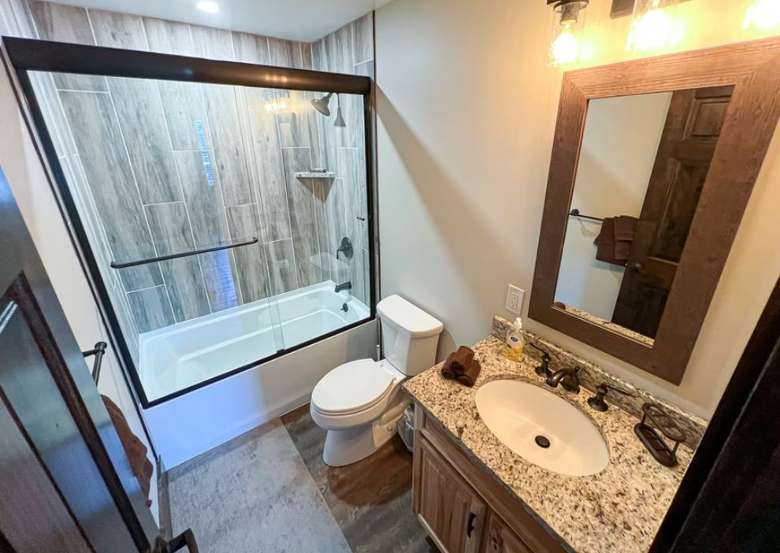a bathroom with a toilet, a shower and tub, a sink, and a mirror