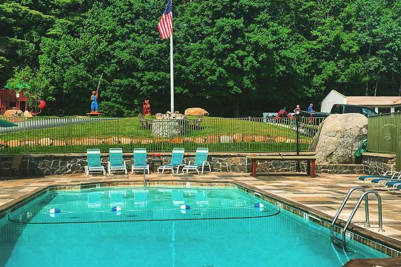 an outdoor pool with chairs near it and an American flag in the background on a flagpole