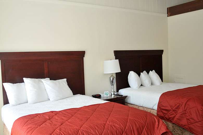 two beds in a bedroom with red and white bedspreads