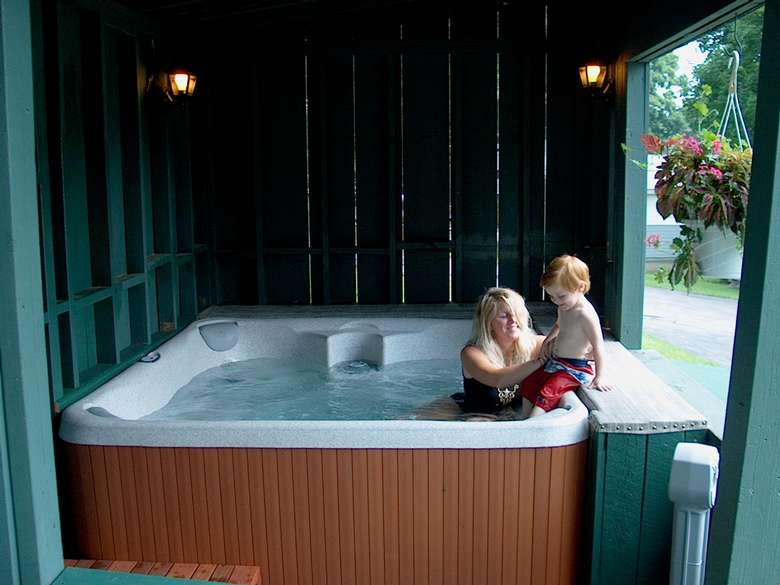 woman in hot tub easing her little boy in