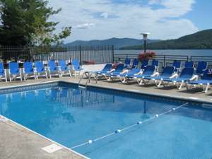 blue lounge chairs surrounding a pool overlooking lake george