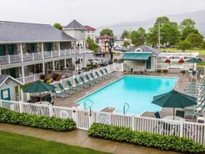 The exterior of the Quality Inn - Lake George, showing the inground pool, surrounding pool deck, and some of the rooms.
